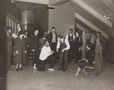 Woman sitting, in the face of a man, kneeling on the indoor standing next to a man and a woman
